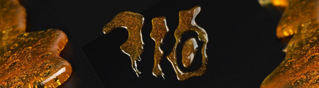 A close-up of amber-colored resin with a stylized, dripping text design in the center, set against a dark background.