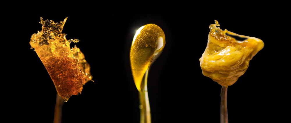 Three distinct blobs of amber-colored substances on sticks, set against a black background.